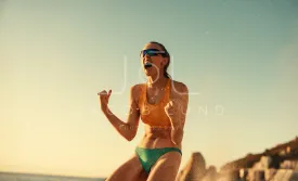 Australian female beach volleyball player celebrating victory on coastal beach