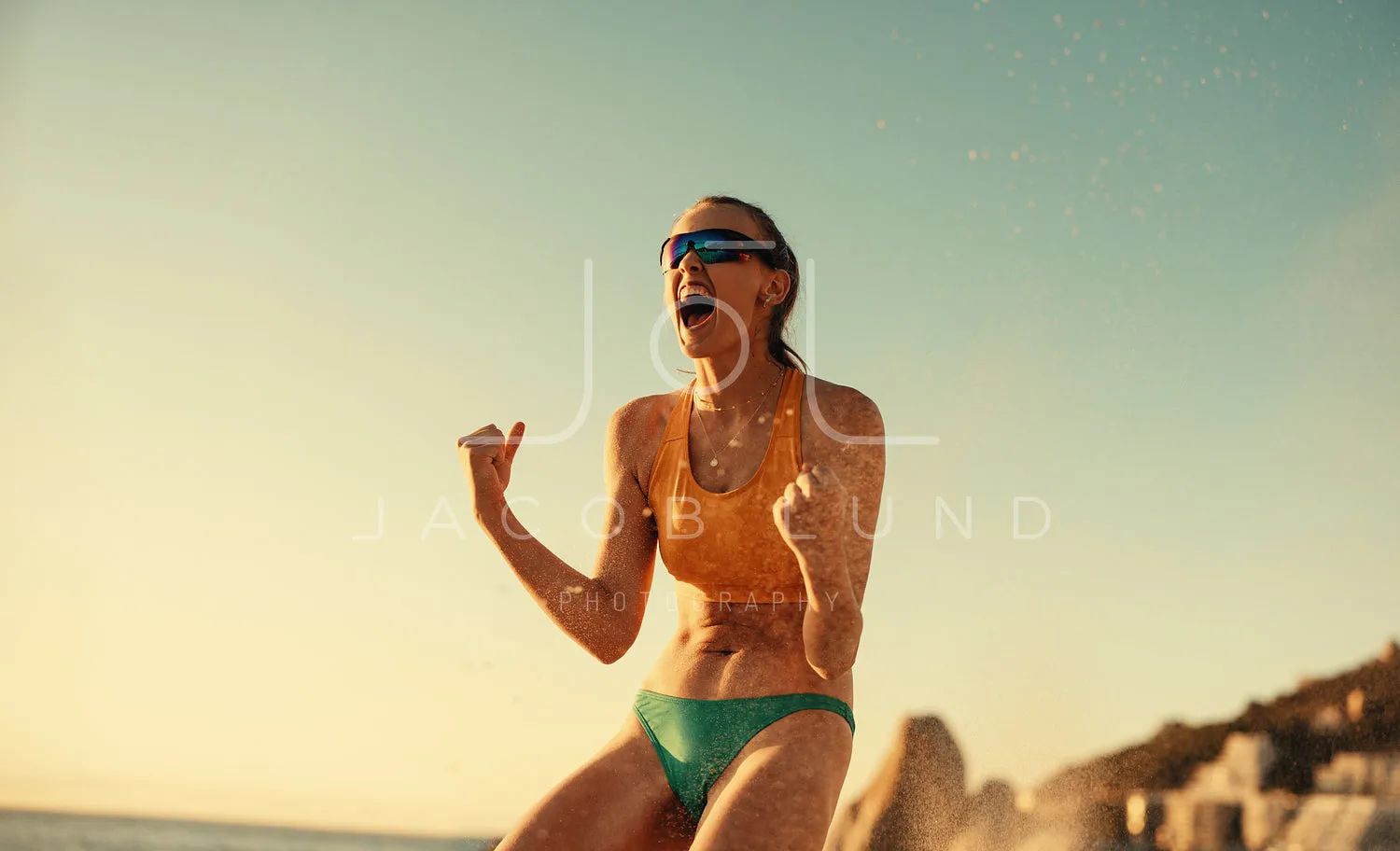 Australian female beach volleyball player celebrating victory on coastal beach