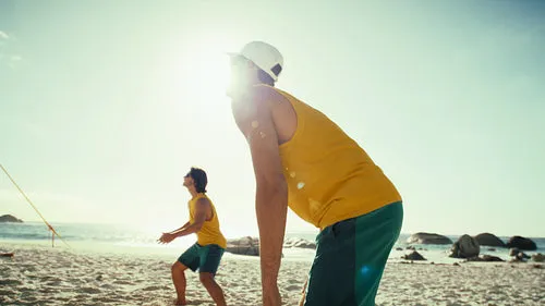 Dynamic handheld shot of professional sportsmen displaying teamwork on beach volleyball court